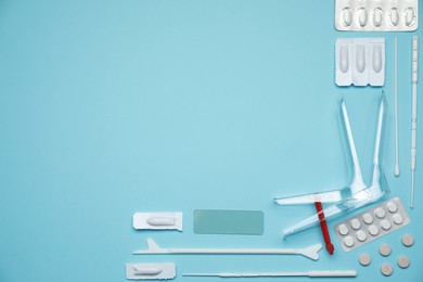 Sterile gynecological examination kit and pills on light blue background, flat lay. Space for text