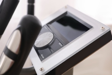 Control panel of modern elliptical machine cross trainer on blurred background, closeup