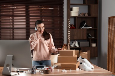 Photo of Shoes seller talking on phone in office. Online store