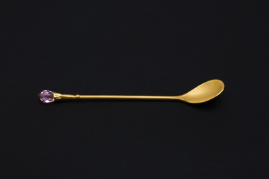 Shiny luxury gold spoon on black background