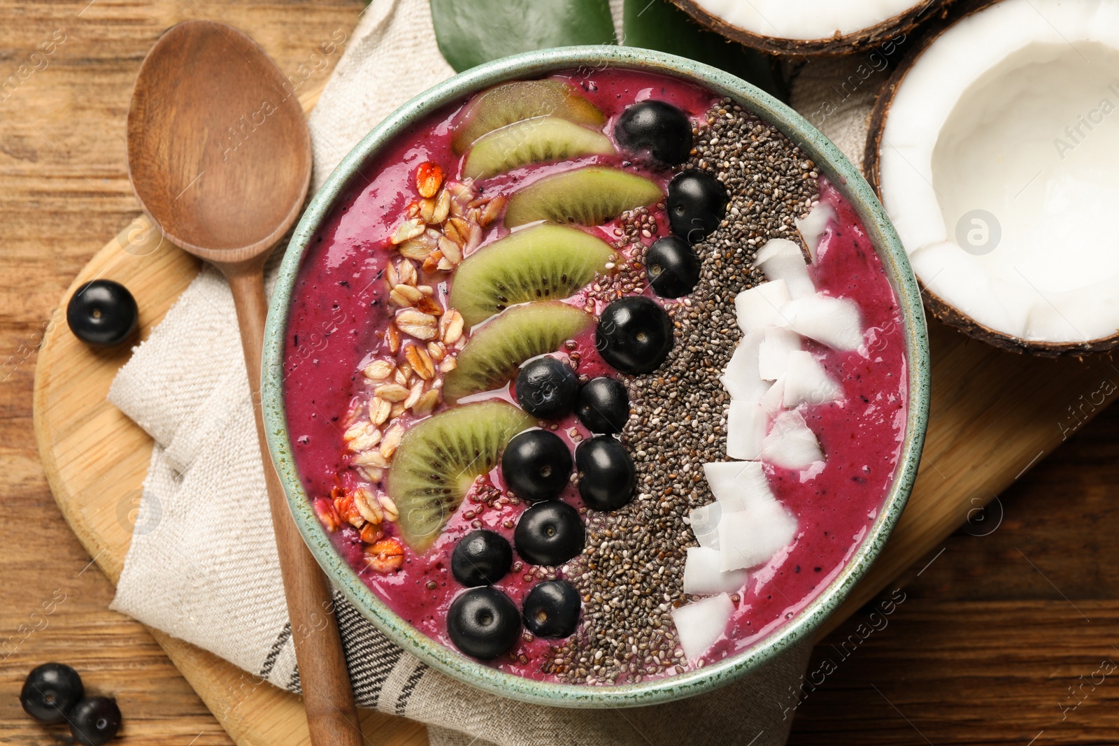 Photo of Delicious acai smoothie and fruits in bowl served on wooden table, flat lay