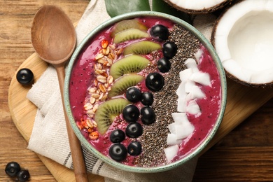 Photo of Delicious acai smoothie and fruits in bowl served on wooden table, flat lay