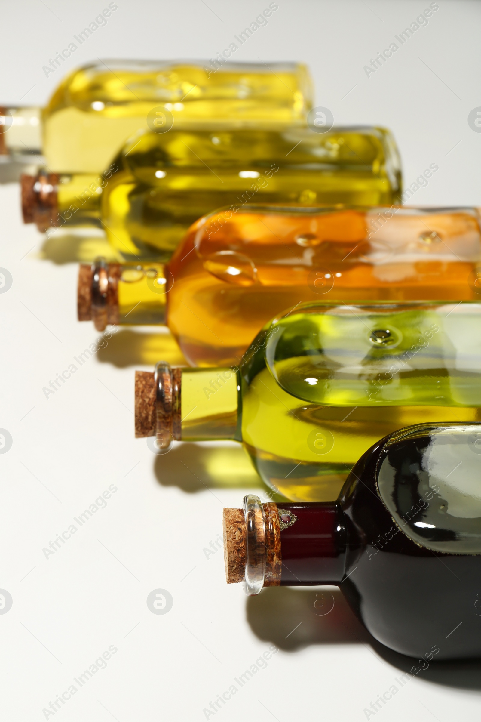 Photo of Vegetable fats. Different cooking oils in glass bottles on white background