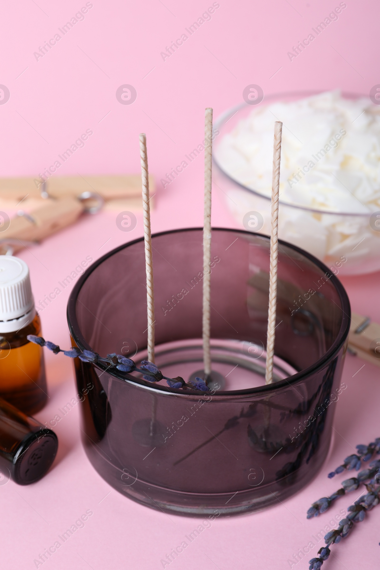 Photo of Container with wicks and lavender flowers on pink background. Making homemade candle