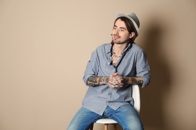 Photo of Young man with tattoos on body against beige background