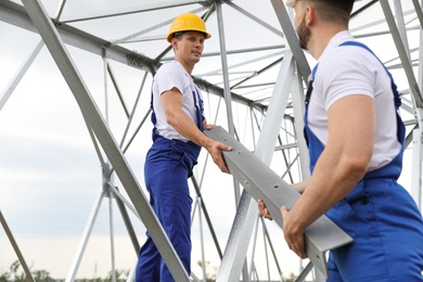 Workers building high voltage tower construction outdoors. Installation of electrical substation