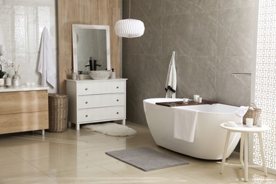 Photo of Modern white tub and chest of drawers with sink in bathroom. Interior design