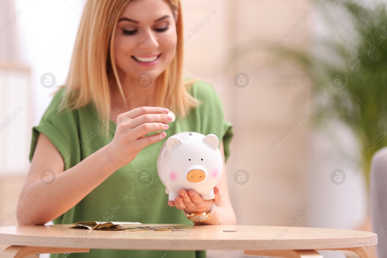 Photo of Woman with piggy bank and money at home. Space for text
