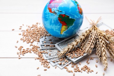 Photo of Globe, ears of wheat and banknotes on white wooden table. Import and export concept