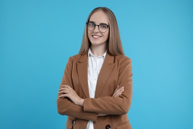 Photo of Happy young secretary with crossed arms on light blue background