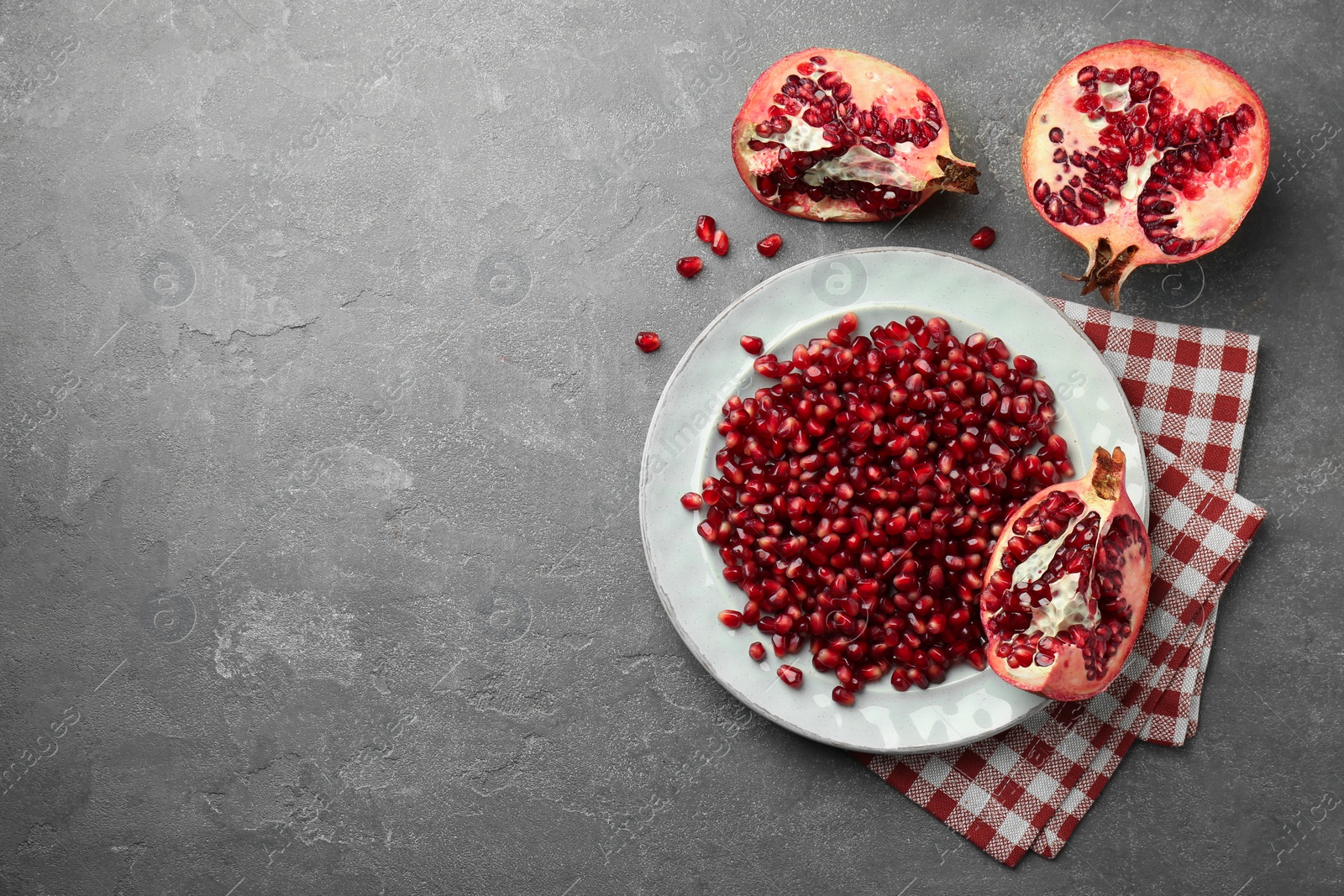 Photo of Tasty ripe pomegranate and grains on grey table, flat lay. Space for text