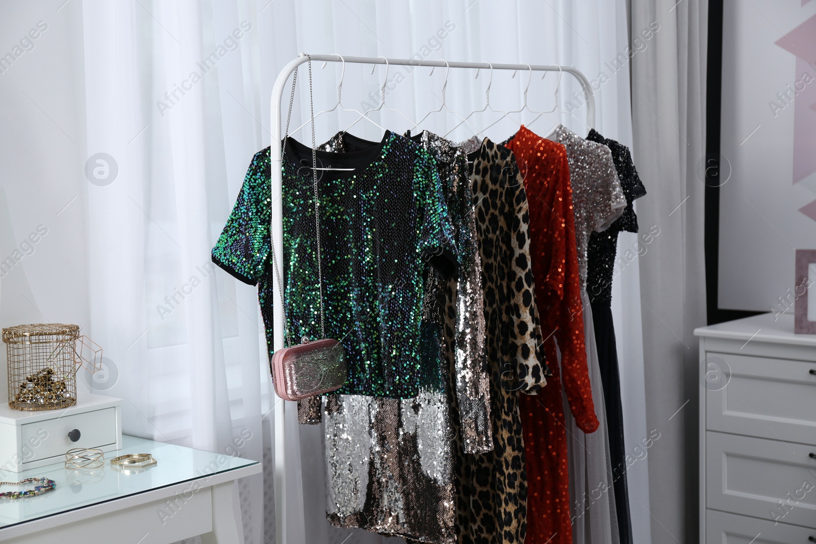 Photo of Rack with collection of beautiful festive clothes in stylish room interior