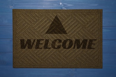 Door mat with word Welcome on blue wooden floor, top view