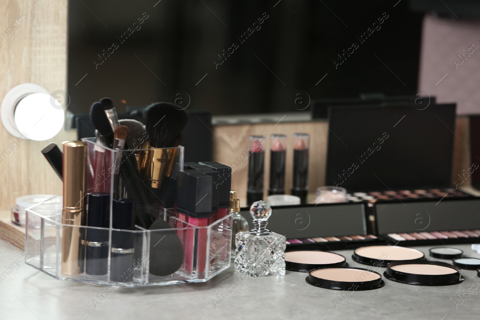 Photo of Different makeup products and accessories on dressing table in room interior