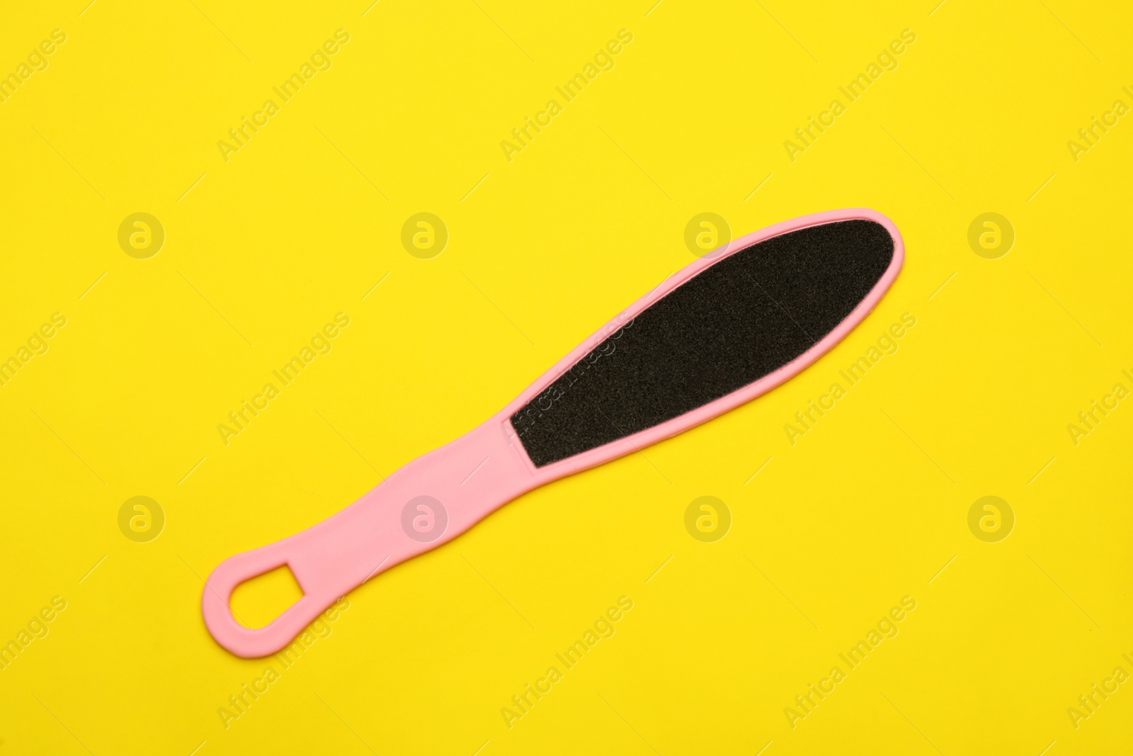 Photo of Pink foot file on yellow background, top view. Pedicure tool