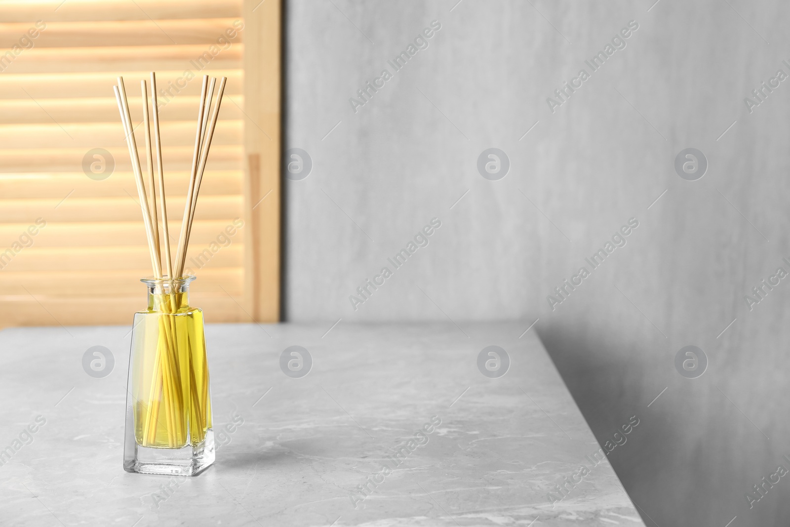 Photo of Aromatic reed freshener on grey table, space for text