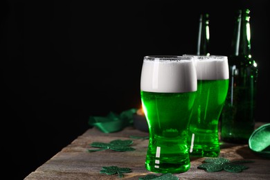 Photo of St. Patrick's day party. Green beer and decorative clover leaves on wooden table. Space for text