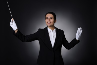 Photo of Happy professional conductor with baton on black background