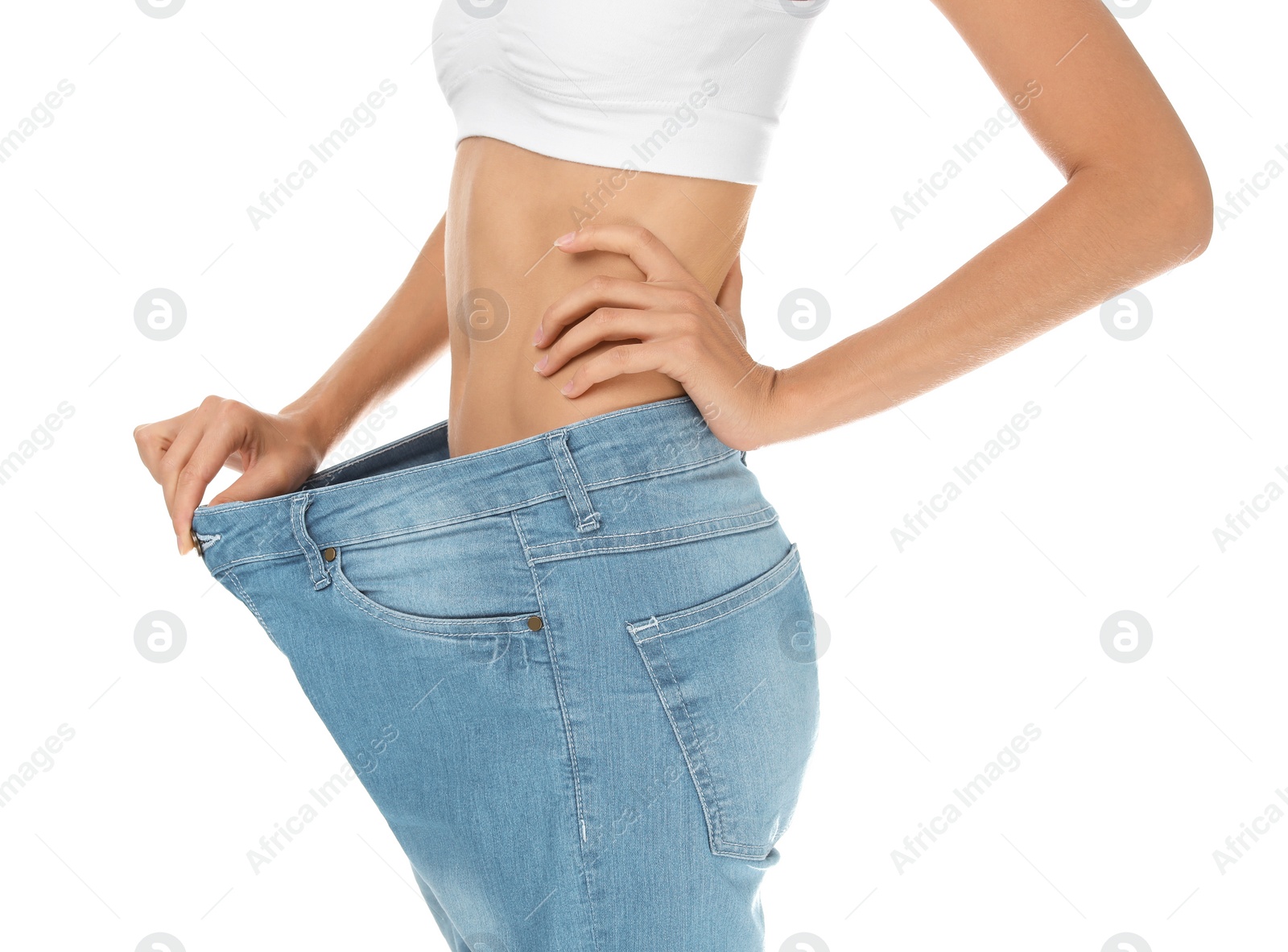 Photo of Young slim woman in old big jeans showing her diet results on white background