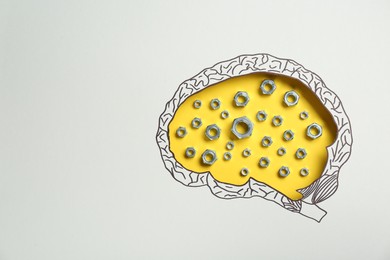 Analytical thinking. Nuts on yellow background, top view through paper with brain shaped hole and drawing. Space for text