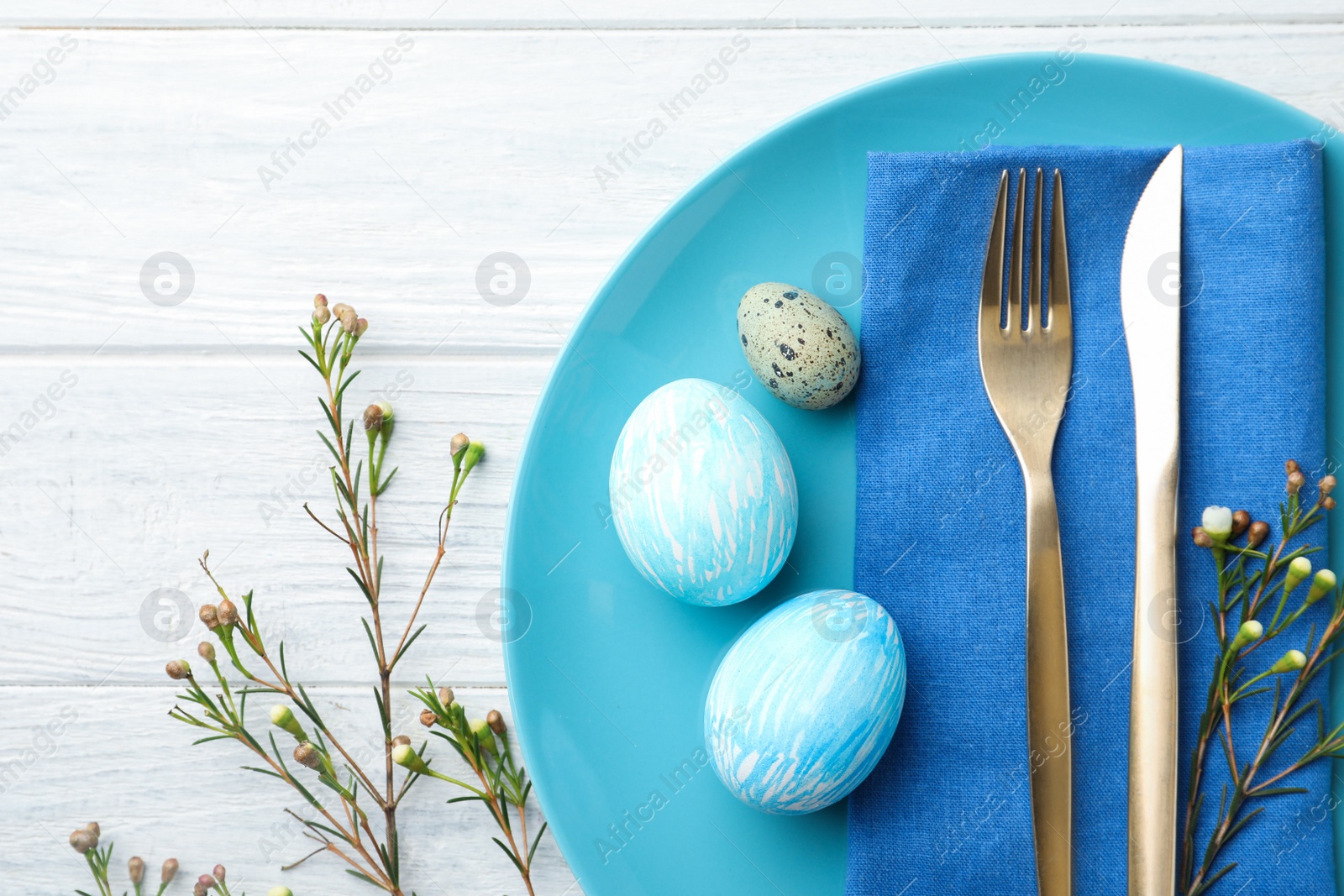 Photo of Festive Easter table setting with eggs and floral decoration on wooden background, flat lay
