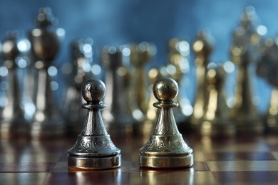 Pawns in front of chess pieces on checkerboard, selective focus