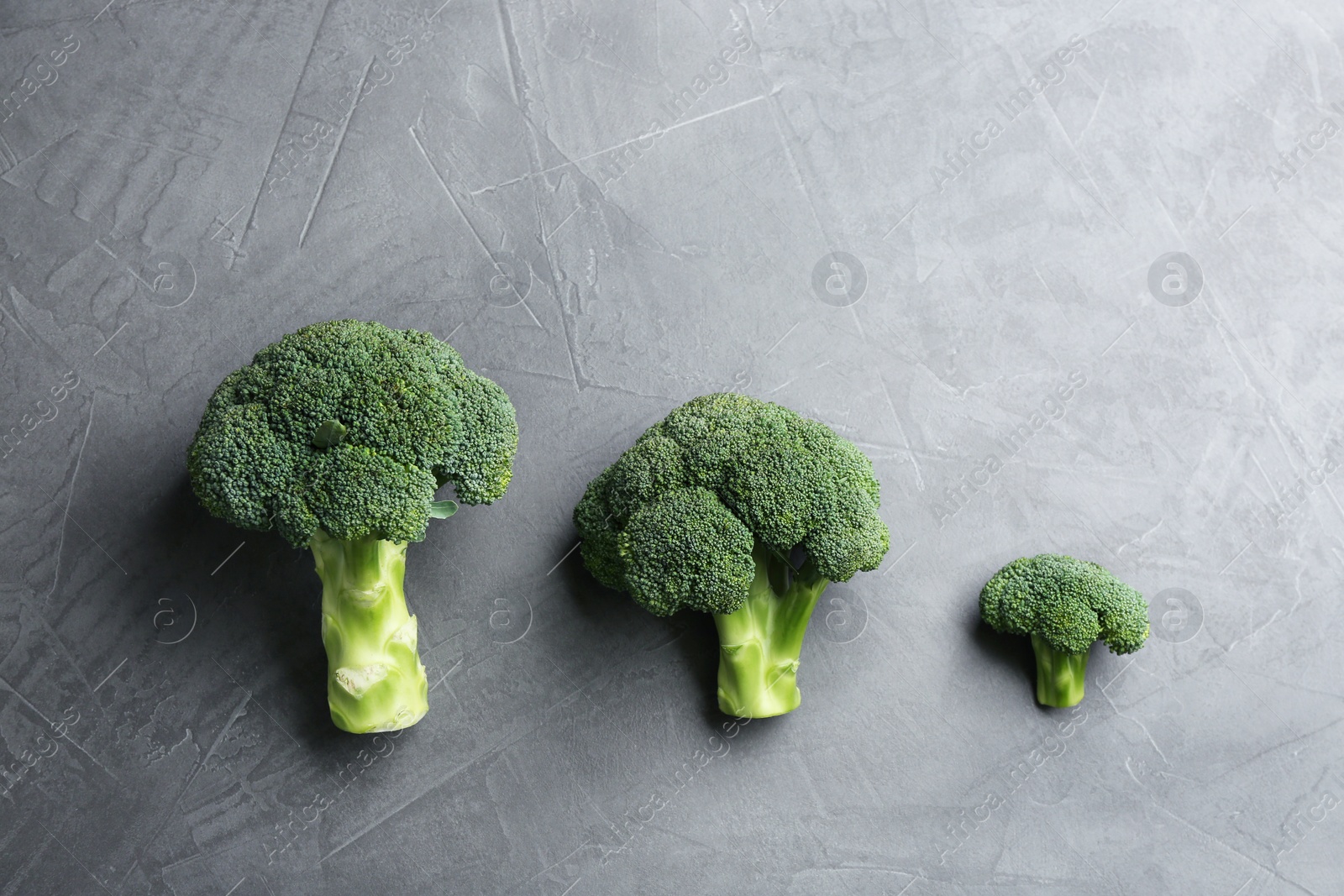 Photo of Fresh broccoli florets on grey table, flat lay