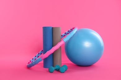 Photo of Hula hoop, exercise ball, yoga mats and dumbbells on pink background