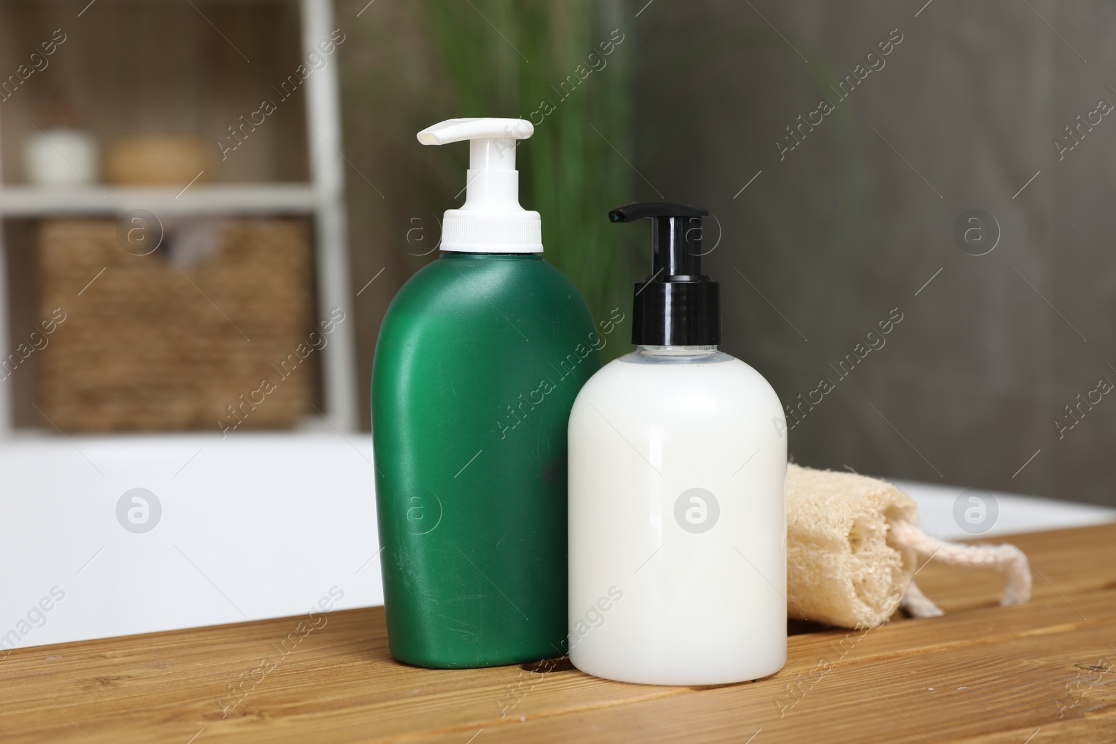 Photo of Bottles of shower gels and loofah on wooden table indoors