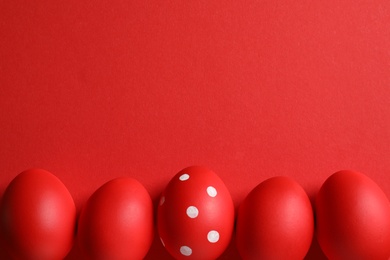 Flat lay composition of red painted Easter eggs on color background, space for text