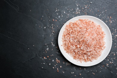 Photo of Pink himalayan salt on black table, flat lay. Space for text