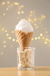 Sweet cotton candy in waffle cone on table against blurred lights