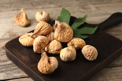 Board with tasty dried figs and green leaf on wooden table