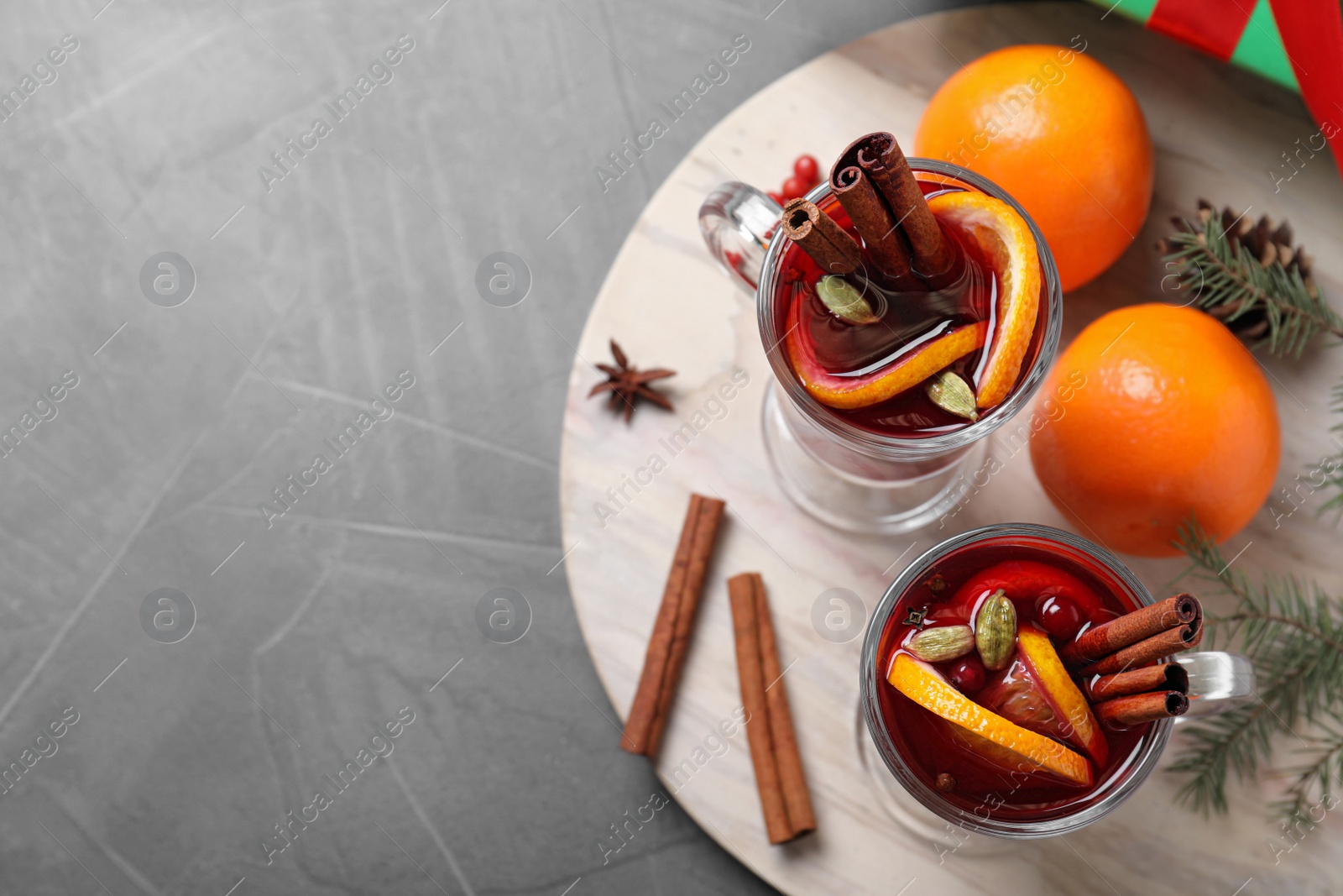 Photo of Glass cups of tasty mulled wine on grey table, flat lay. Space for text