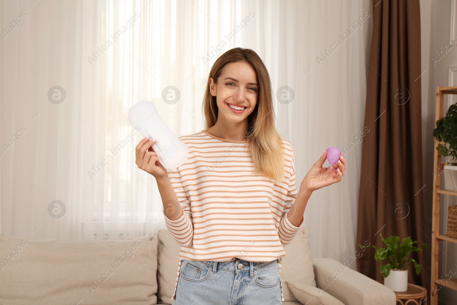 Photo of Young woman with menstrual cup and disposable pad at home