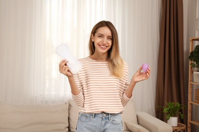 Photo of Young woman with menstrual cup and disposable pad at home