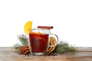 Photo of Composition with glass cup of mulled wine, cinnamon, orange and fir branch on table against white background. Space for text
