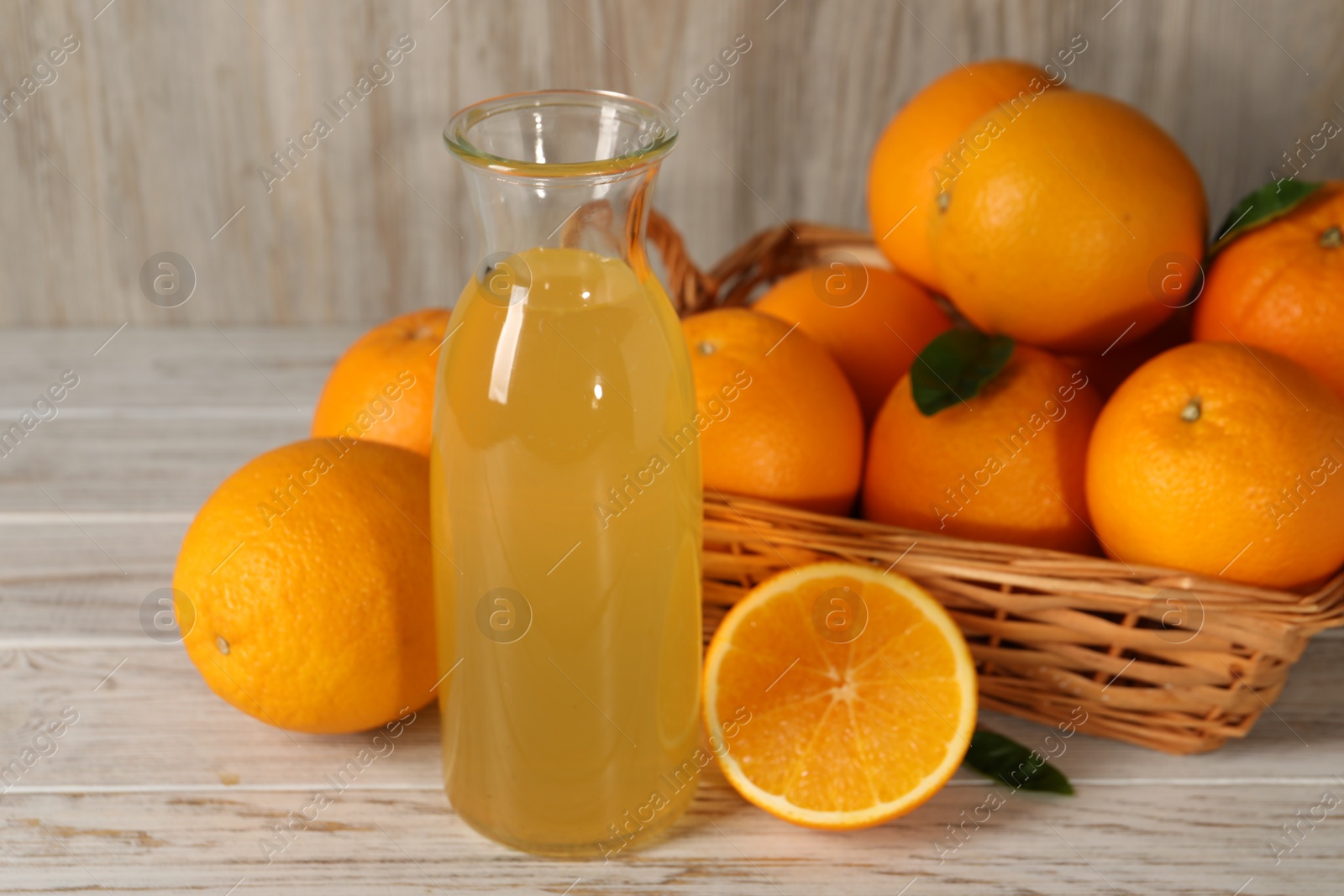 Photo of Many ripe oranges and fresh juice on light wooden table