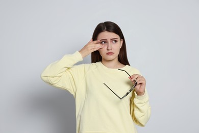 Photo of Young woman suffering from eyestrain on light background
