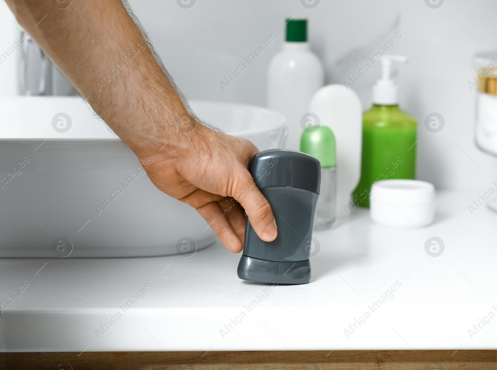 Photo of Man holding stick deodorant in bathroom, closeup view