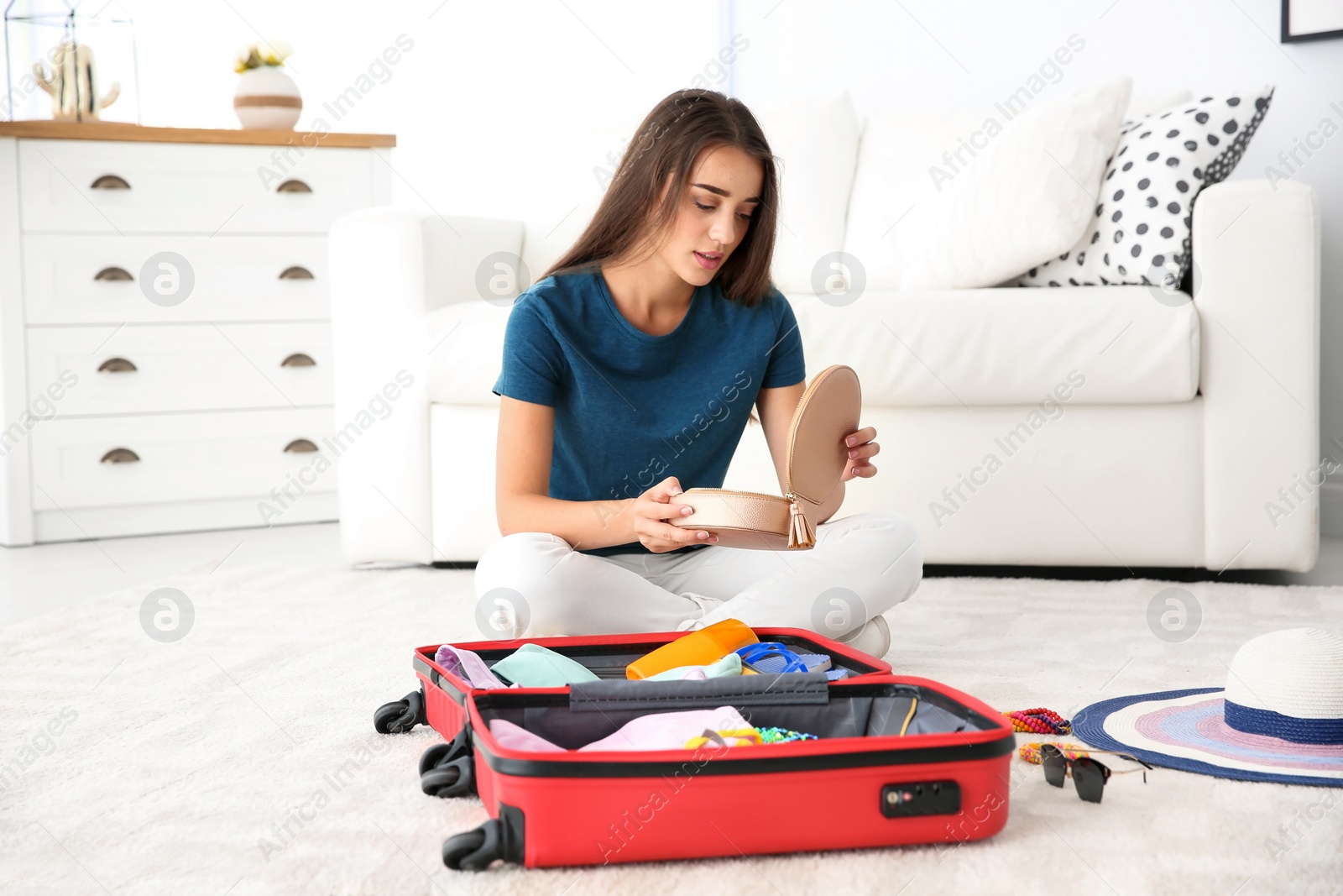 Photo of Young woman packing suitcase for summer journey at home