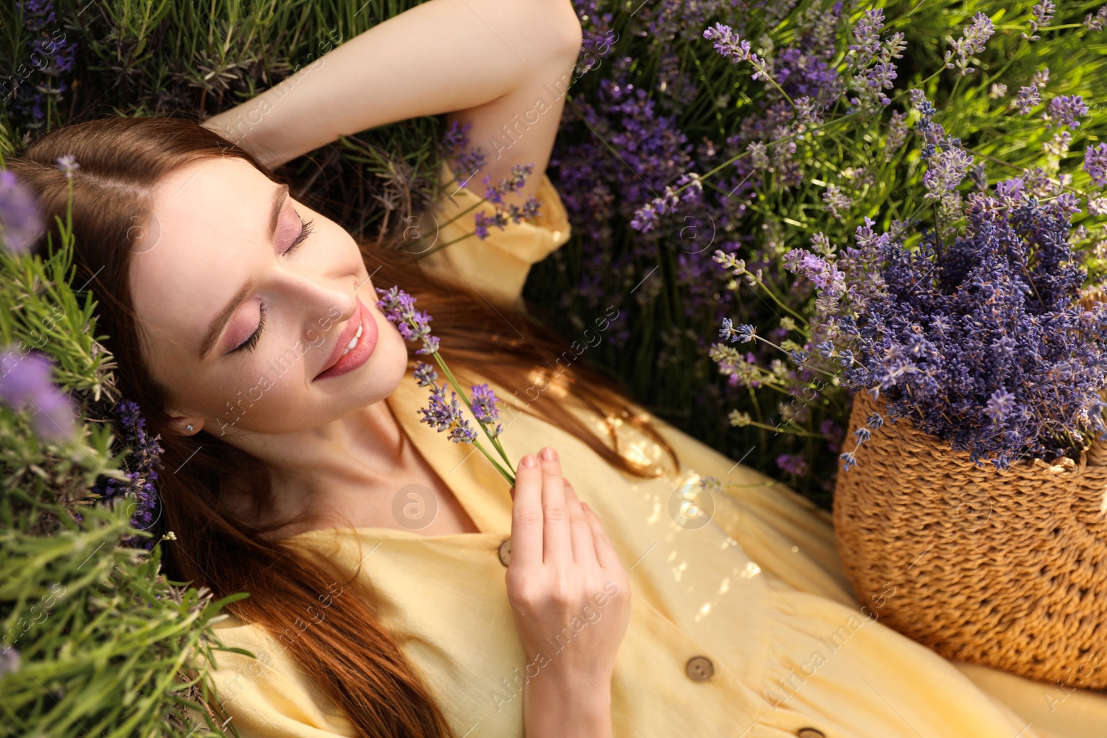 Photo of Young woman lying in lavender field on summer day