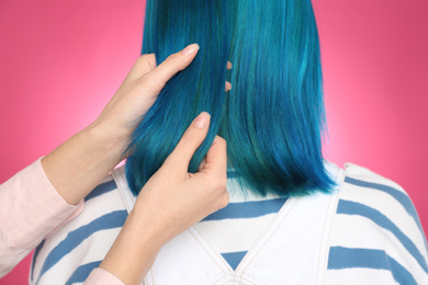 Photo of Woman with bright dyed hair on pink background, back view