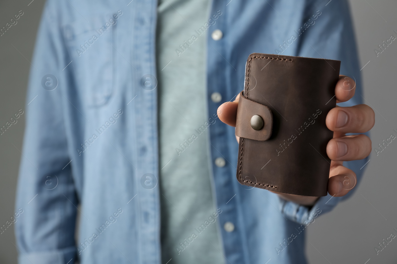 Photo of Man holding leather business card holder on grey background, closeup