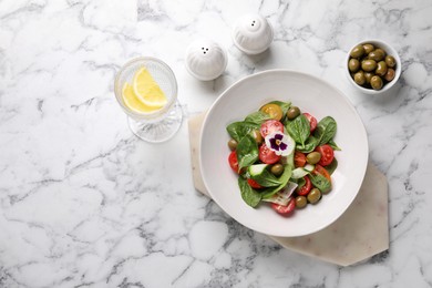 Photo of Delicious salad with vegetables and olives served on white marble table, flat lay. Space for text