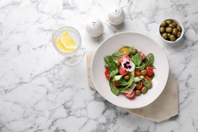 Delicious salad with vegetables and olives served on white marble table, flat lay. Space for text