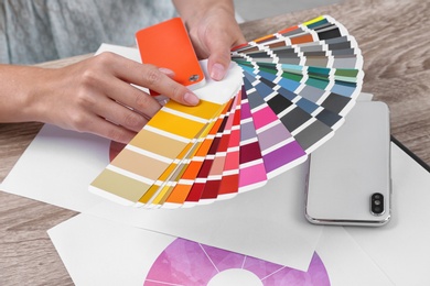 Photo of Woman with color palette samples at table, closeup