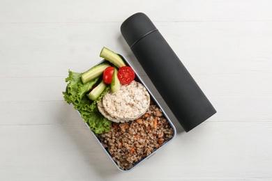 Photo of Thermos and lunch box with food on white wooden background, flat lay