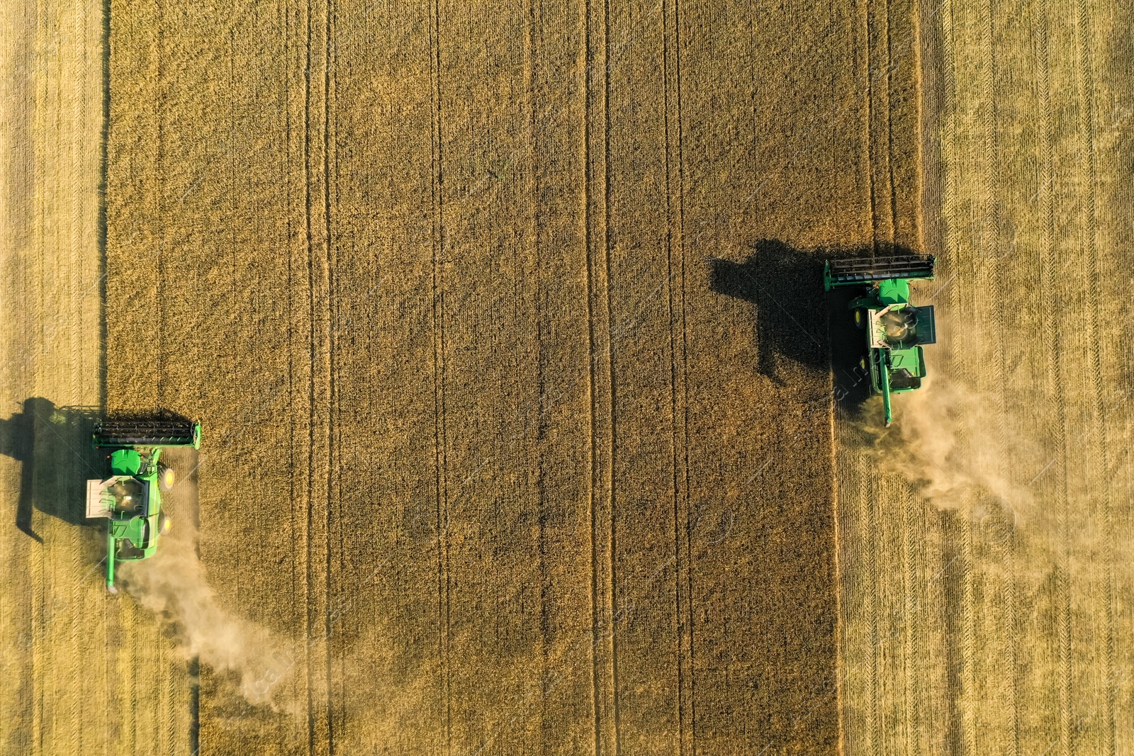 Photo of Beautiful aerial view of modern combine harvesters working in field on sunny day. Agriculture industry