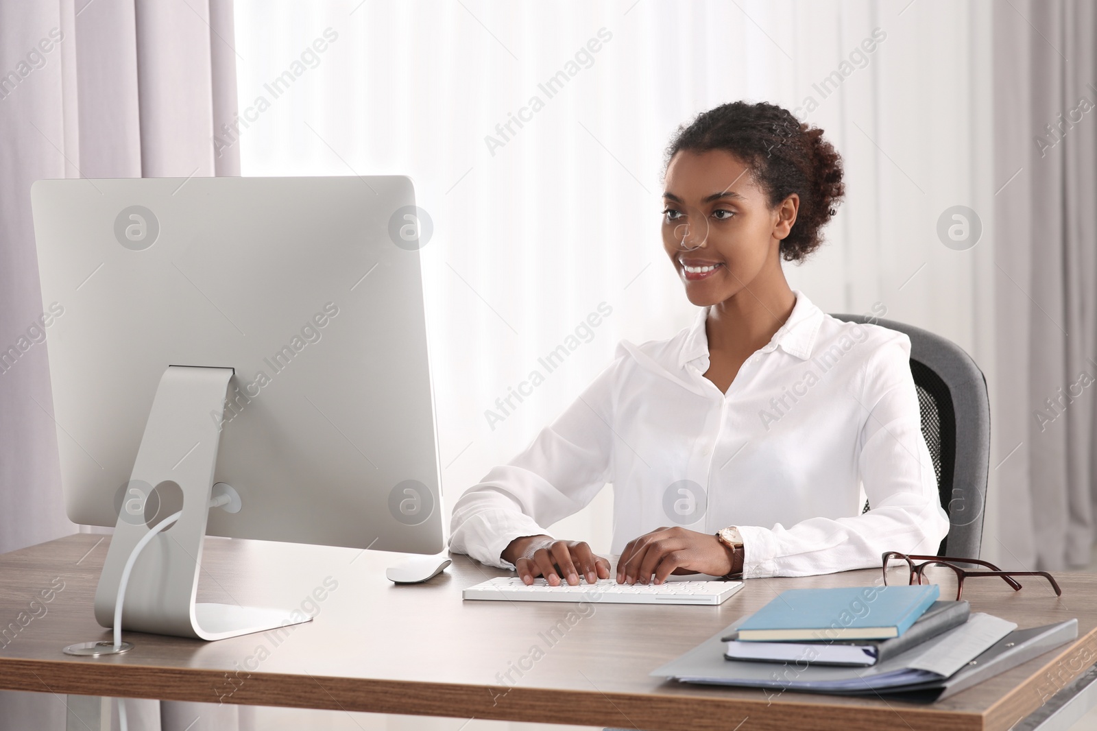 Photo of Smiling African American intern working with computer at table in office